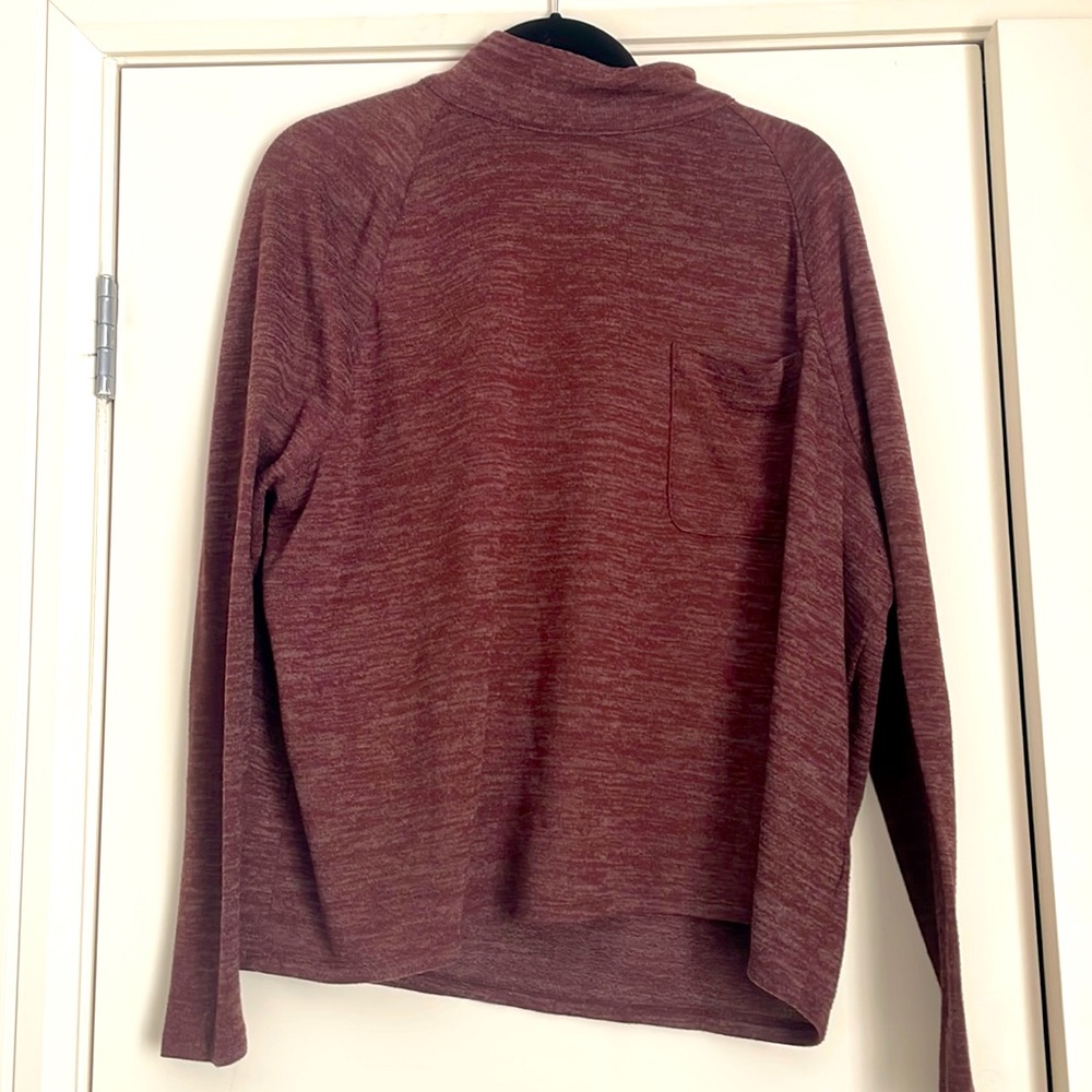 Burgundy colored long sleeved high neck top with front pocket on the chest.